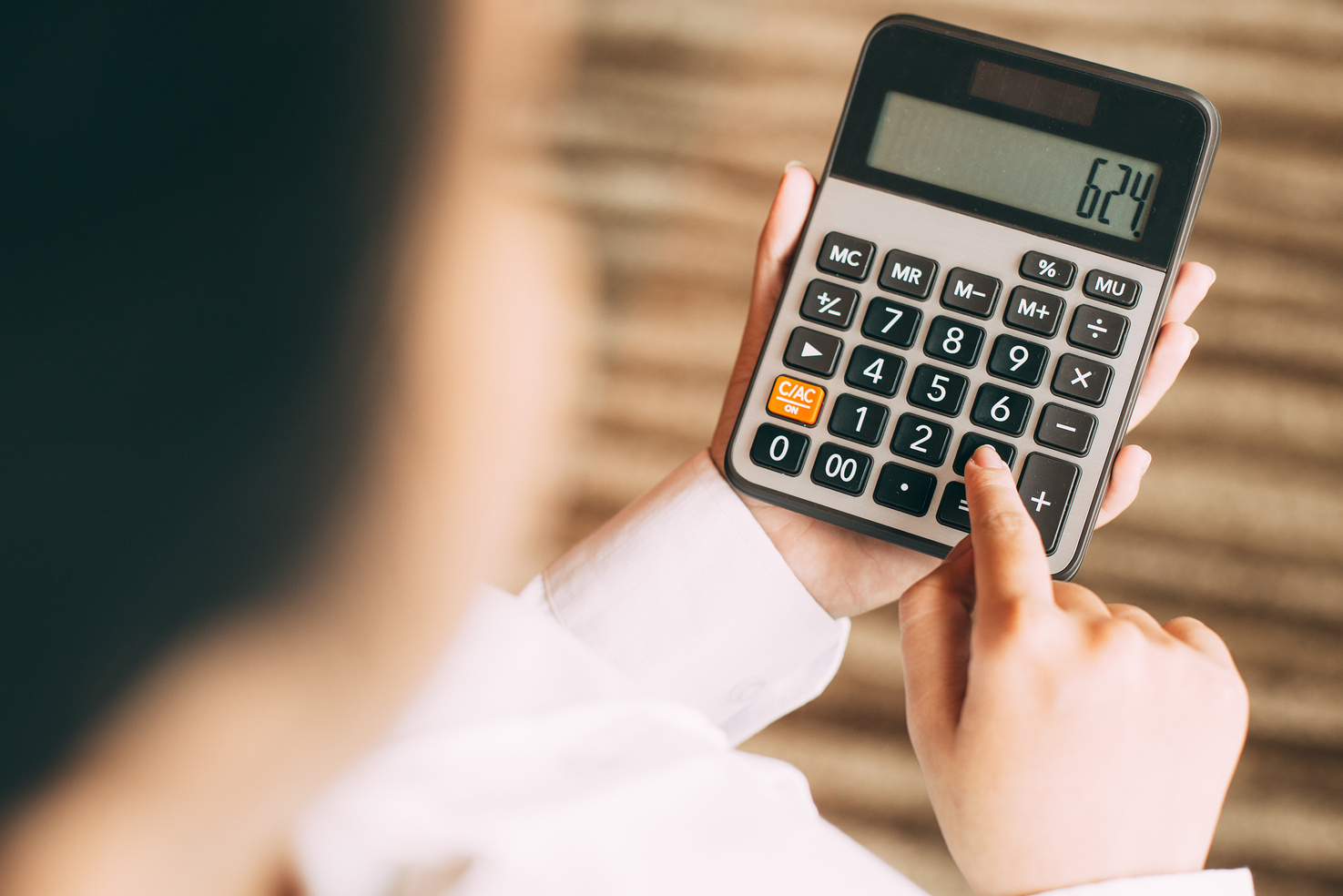 Businesswoman counting with calculator in office
